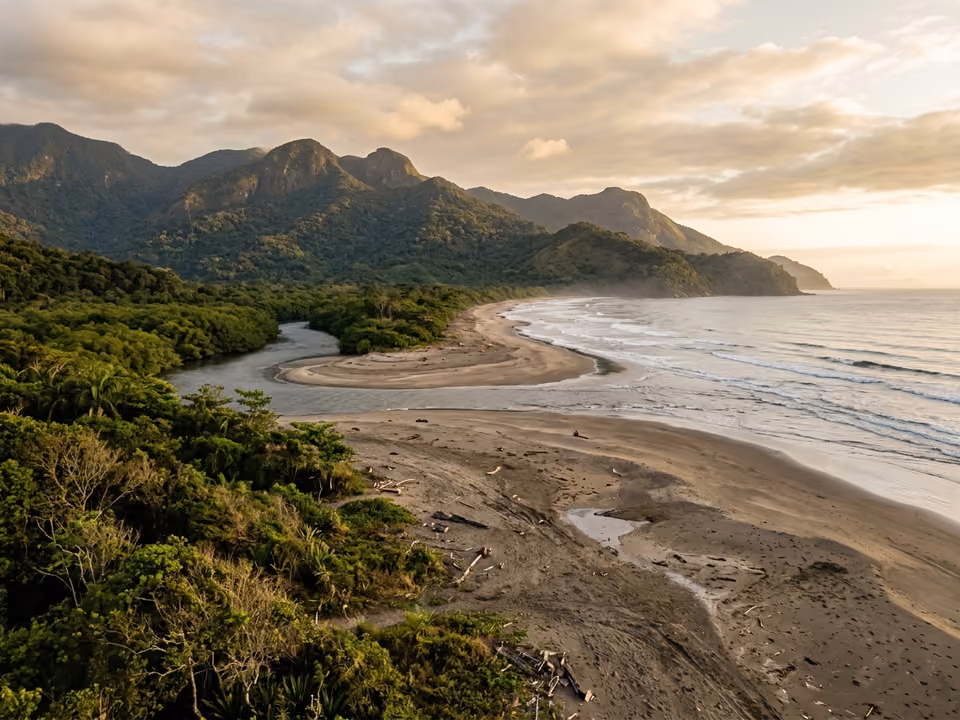 Imensa praia deserta da Fazenda com vegetação de restinga, rio de mangue e montanhas ao fundo