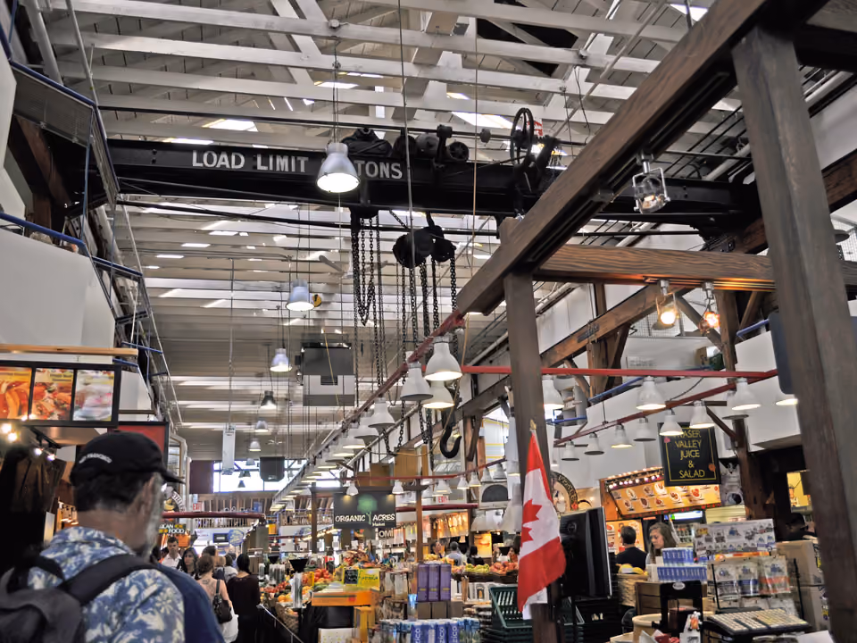 Interior do mercado público de Granville Island, em Vancouver, com barracas de produto fresco e comida pronta