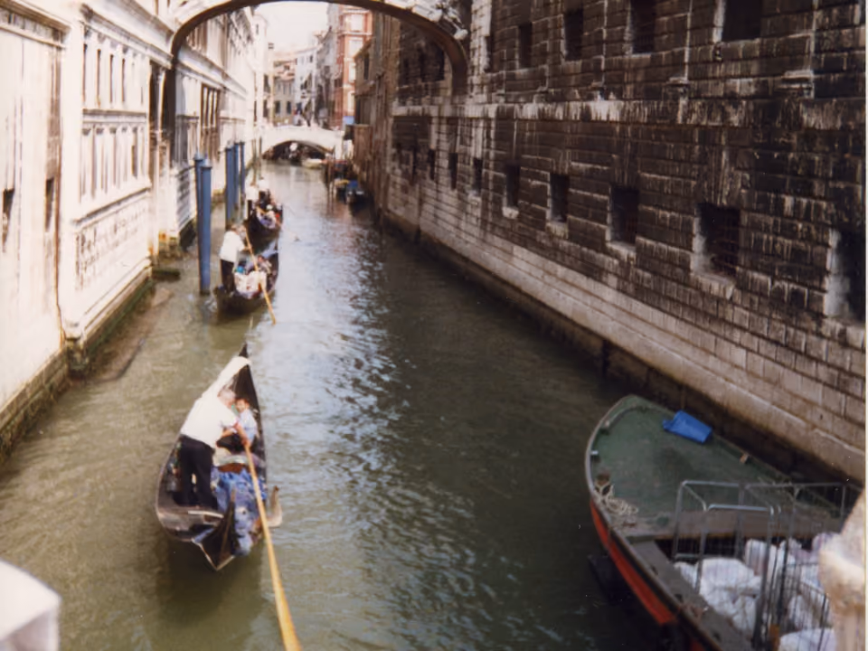 Gondoleiro conduzindo uma gôndola tradicional pelo Grande Canal de Veneza, entre os palácios históricos à beira da água