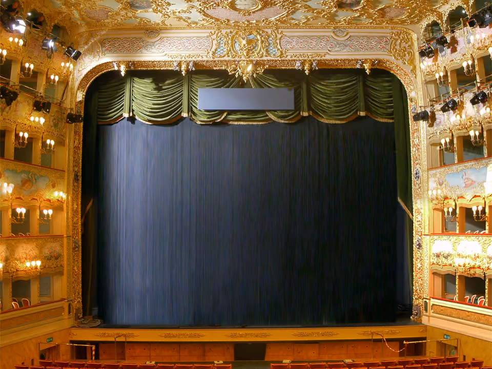 Interior dourado do Teatro La Fenice em Veneza, com os camarotes decorados e o teto pintado