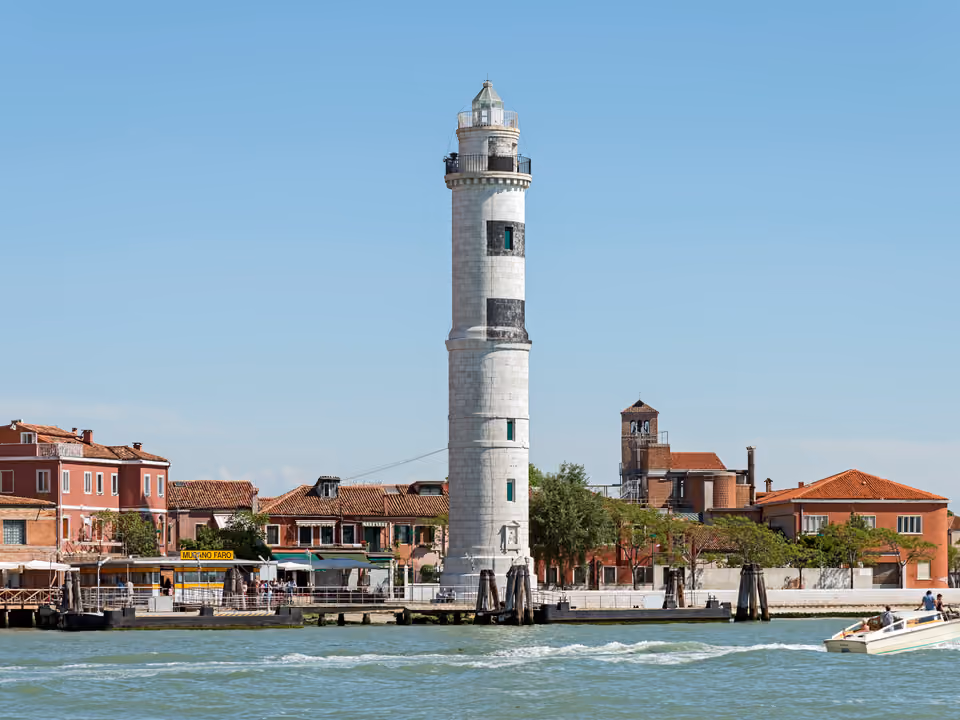 Farol histórico da ilha de Murano perto de Veneza, à beira da água, com casas coloridas ao redor