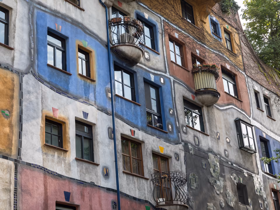 Fachada colorida e irregular da Casa Hundertwasser em Viena, com formas onduladas e vegetação nas sacadas