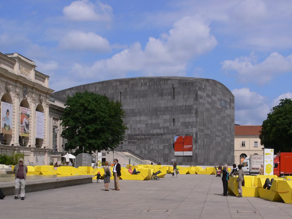 Pátio interno do MuseumsQuartier em Viena, com os prédios barrocos convertidos em museus e pessoas sentadas nos bancos ao ar livre