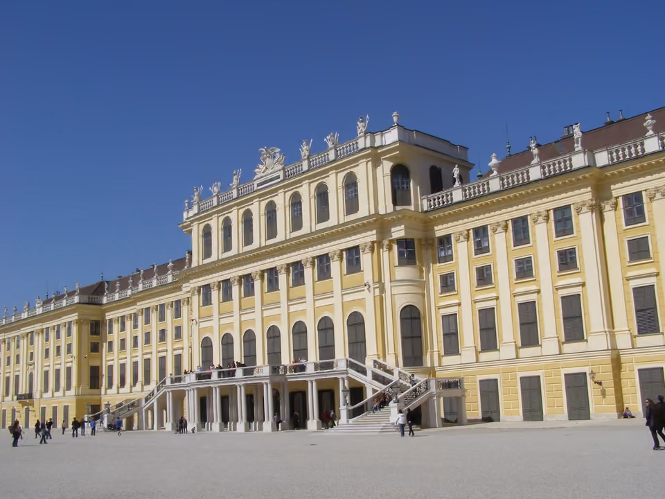 Fachada amarela do Palácio de Schönbrunn em Viena, com o jardim formal e a fonte de Netuno em primeiro plano